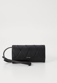Clutch in pelle nera con trapuntatura a diamante, una tracolla staccabile e un sottile logo Calvin Klein sul davanti. Texture liscia.