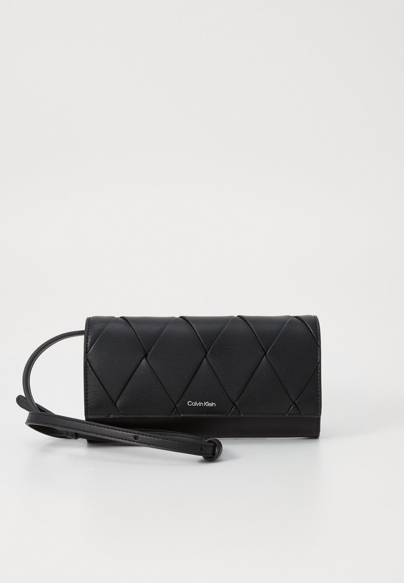 Clutch in pelle nera con trapuntatura a diamante, una tracolla staccabile e un sottile logo Calvin Klein sul davanti. Texture liscia.
