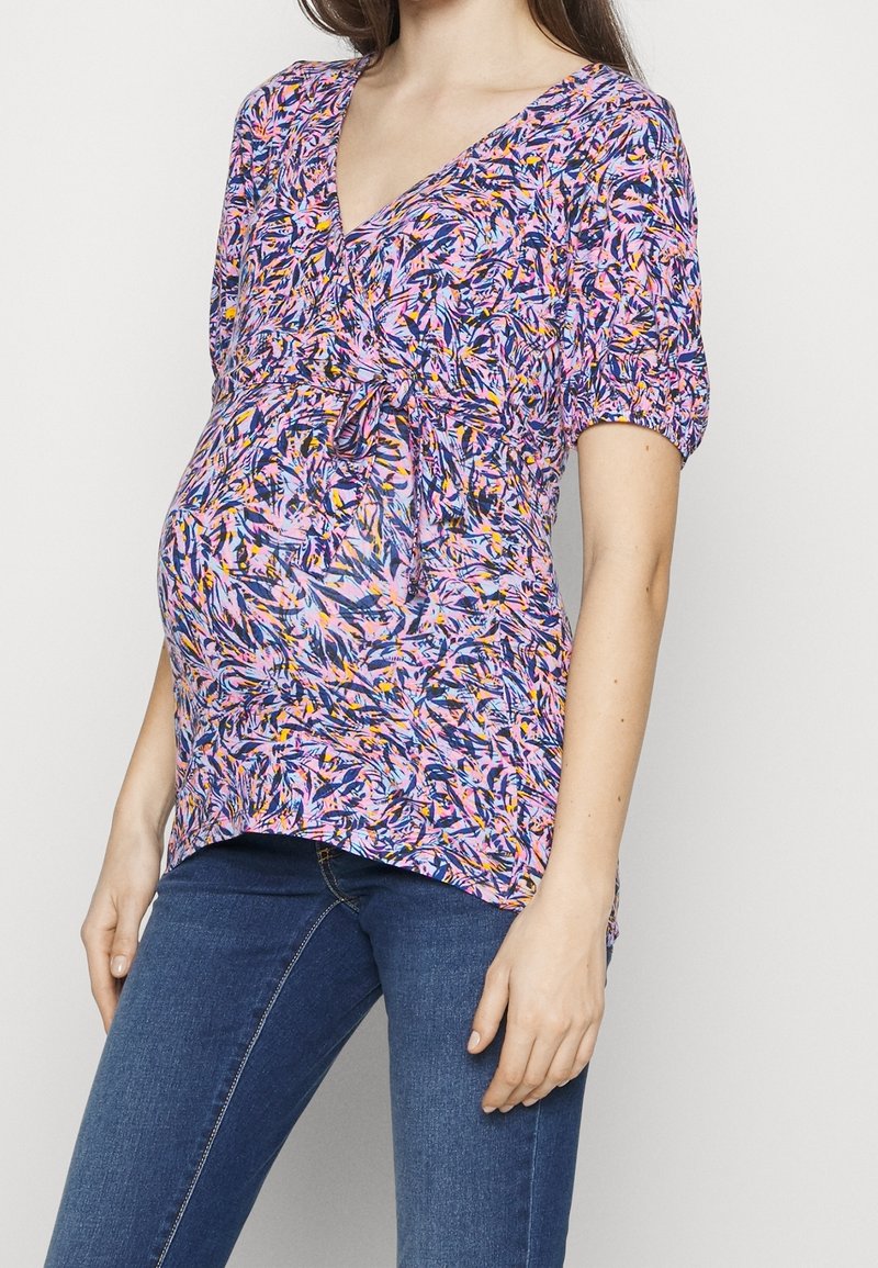 Těhotenský top v barevném, abstraktním vzoru s výstřihem do V, krátkými nabíranými rukávy a nařasením v pase.