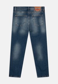 Calças de ganga em azul escuro com um acabamento desbotado. Apresenta um design de perna reta, cinco bolsos e um patch de pele na cinta.