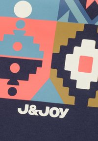 Kleurvolle J&Joy-stof met geometrische patronen in roze, blauw, wit en bruin. Zachte textuur met zichtbare afdrukdetails.