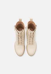 Beżowe botki za kostkę z gładkiej skórzanej cholewki, okrągłym noskiem, sznurówką z przodu, bocznym zamkiem błyskawicznym i jasnobrązowym wnętrzem. Płaska podeszwa i minimalne detale.