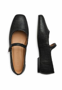 Bailarinas negras con estampado de cocodrilo, con punta cuadrada, parte superior de cuero y un corte lateral. Presentan una correa decorativa a lo largo del empeine.