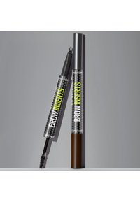 Maquillage des sourcils à double embout avec pinceau goupillon d'un côté et applicateur à plusieurs pointes de l'autre, étiqueté « Brow Inserts » par Maybelline.