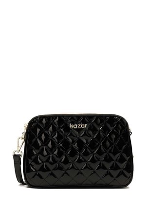 Bolso de mano de patente negro acolchado con herrajes plateados, cierre con cremallera y correa desmontable. Presenta el logotipo distintivo grabado en la parte frontal.