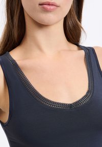 Navy sleeveless top with a scoop neckline, featuring a delicate lace trim. The material appears smooth and fitted.
