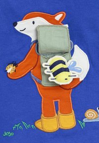 Broderad design av en räv i en orange dräkt som håller en bi, med en grön ryggsäck, mot en blå bakgrund. Inkluderar gräs och en snigel.