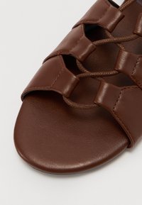 Ruske nahkasaapad, joissa on litteä pohja, kudottu hihnasuunnittelu ja teksturoitu koriste smoothilla pinnalla.