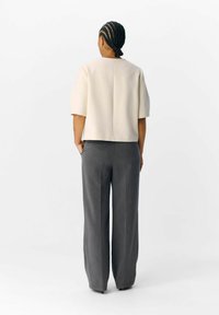 Haut blanc à manches courtes avec une coupe droite, associé à un pantalon large gris présentant de légères rayures. Design simple, sans motifs visibles.