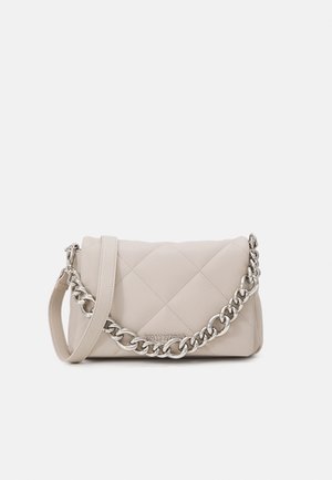 Lyse beige quiltet håndtaske med sølvkæde detalje og matchende skulderrem på en ensfarvet lys baggrund.