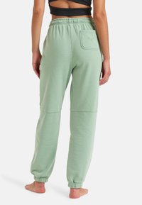 Lysegrønne sweatpants med elastisk talje, afsluttede sømme og en baglomme med hjerteprint. Blødt stof med en afslappet pasform.