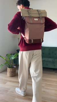 Rucksack mit pinker Außenseite, beigem Deckel und braunem Boden. Verfügt über verstellbare Träger, ein Logopatch und einen Rolltopverschluss.