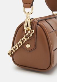 Borsa a mano in pelle marrone con design trapuntato, hardware color oro e un accento in catena. La cerniera e la tracolla regolabile sono dettagli prominenti.