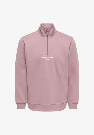 Pullover-genser i lyserosa med kvartglidelås, ribbestrikkede mansjetter og hvit logo med teksten "CURATED STAPLES" på framsiden.