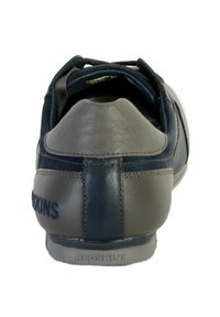 Zapatilla en azul marino y gris con materiales de piel y tela. Incluye un logo en el talón, parte trasera redondeada y detalles de costura.