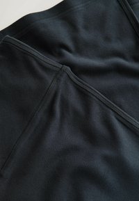 Tela de forro negro con costuras visibles, con textura suave y detalles de costura ligeramente elevados. Sin patrones o acentos distintivos.