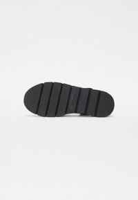 Talpa de cauciuc negru cu o suprafață texturată, având nervuri segmentate pe întreaga lungime și un vârf rotunjit. Marcata cu brandul "Barbour".