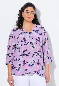 Blusa floreale lavanda con maniche a 3/4, caratterizzata da motivi a foglia blu navy e rosa, scollo rotondo e dettagli con bottoni. Tessuto leggero e fluido.