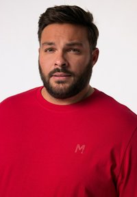 Rotes Kurzarm-T-Shirt aus Baumwolle mit Rundhalsausschnitt. Auf der Brust befindet sich ein dezentes, helleres rotes Logo "M". Glatte Textur.