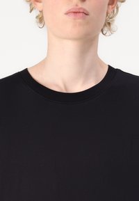 Zwarte katoenen t-shirt met een ronde hals. Heeft een zachte textuur en een slim fit snit, ontworpen voor een minimalistische esthetiek.