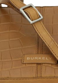 Borsa a mano in pelle marrone con una trama in pelle di coccodrillo, hardware argentato e una tracolla cucita con una fibbia rettangolare.