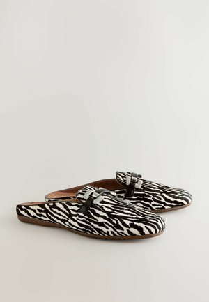 Cipele slip-on s uzorkom zebre u crnoj i bijeloj boji, s glatkom teksturom i metalnim kopčama na gornjem dijelu. Mekan, ravan dizajn potplata.