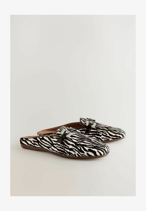 Pantofi slip-on cu imprimeu în dungi de zebră alb-negru, având o textură netedă și accesorii metalice în partea superioară. Design cu talpă moale și plată.