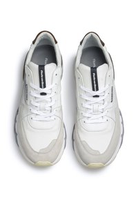 Weiße und hellgraue Sneakers mit einem Obermaterial aus Mesh und Wildleder, ausgestattet mit einer gepolsterten Sohle, runden Schnürsenkeln und dezenten braunen Akzenten an der Ferse.