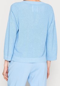 Maglione lavorato a maglia blu chiaro, con una vestibilità morbida, bordo e maniche a costine, superficie testurizzata e senza chiusure visibili.