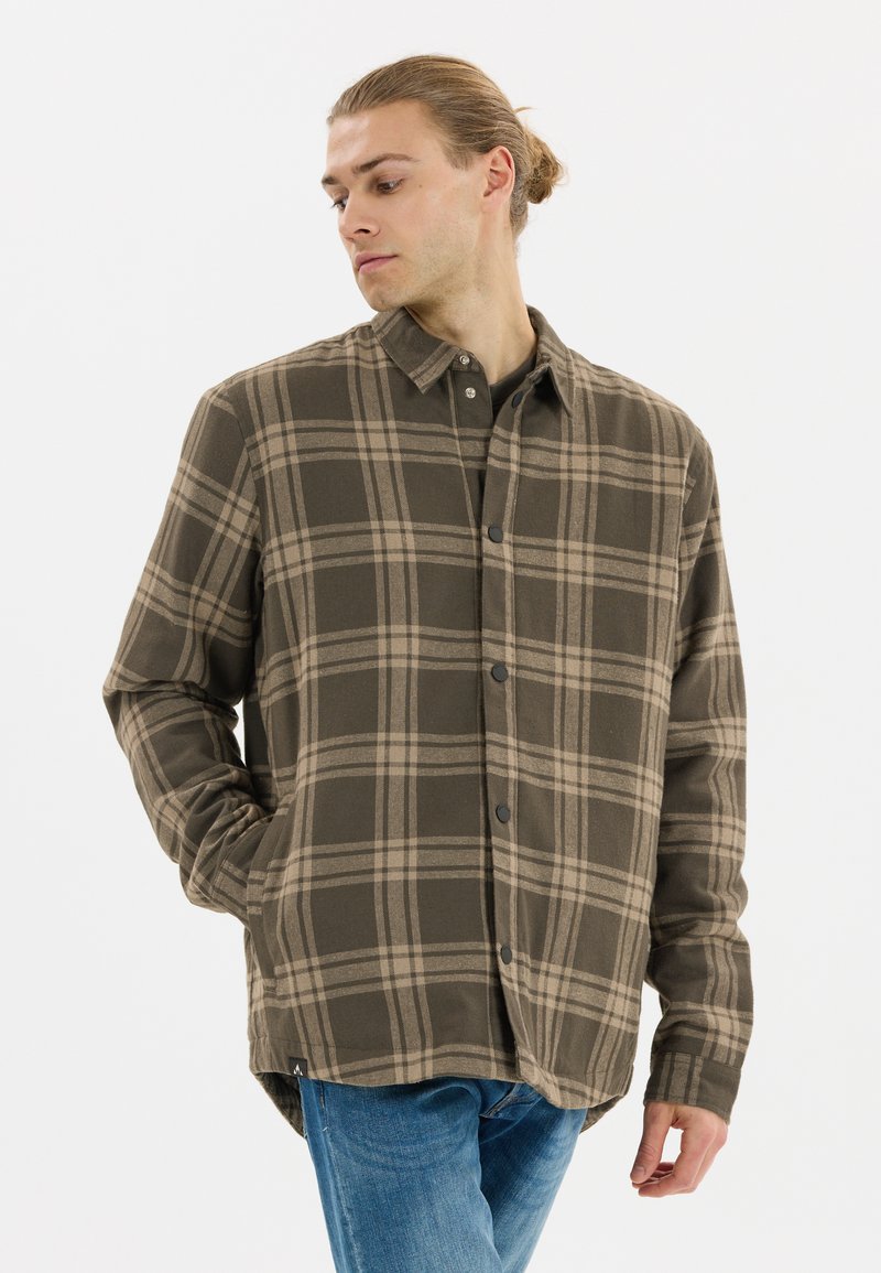 Brun rutigt flanellskjorta med beige linjer, knapp-ner krage och svarta knappar. Mjuk textur, med sidfickor och rundad nederkant.