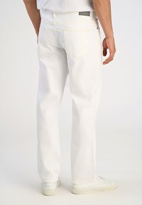 Vaqueros de mezclilla blanca con un diseño de pierna recta, costuras claras, dos bolsillos traseros y un parche de marca negro en la cinturilla.