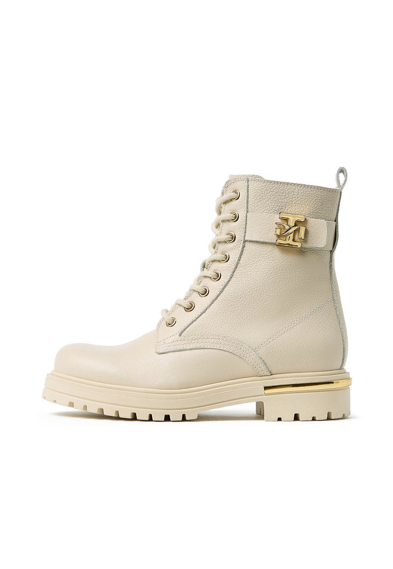 Bottine en cuir beige avec matériel doré, bout rond, devant à lacets et dessus texturé. Dispose d'une semelle épaisse à rainures.