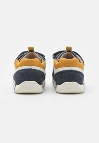 Sneakers in pelle blu navy e senape con finitura in suede testurizzata, dotati di un tassello per il cinturino e un design della suola geometrico. Marchio GEox sul tallone.