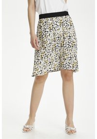 Vloeiende rok met een zwarte basis en witte en gele bloemmotieven. Elastische zwarte tailleband, knielang, gemaakt van lichtgewicht stof.