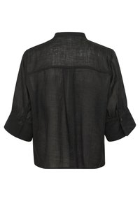 Chemise en lin noire à coupe ample, col rond et manches retroussées avec boutons. Le dos présente une couture horizontale et une texture subtile.