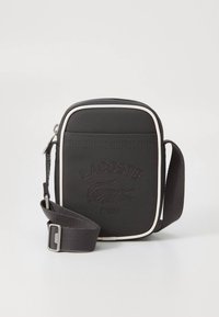 Black rectangular crossbody bag made from textured fabric, featuring white accents, an embossed logo, and an adjustable strap.