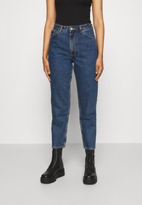 Jeans de mezclilla azul de talle alto con un corte recto, que cuentan con un cierre de botón y cremallera, cinco bolsillos y detalles de costura sutiles.