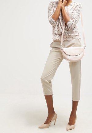Lys pink blonde top med trekvartærmer, beige cropped bukser og matchende spidse hæle, suppleret af en lille lys pink skuldertaske.