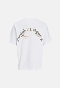 Hvid bomulds T-shirt med teksten "originals atelier" i mørke og lyse farver, med "creative dept." i orange. Korte ærmer og afslappet pasform.