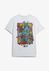 Camiseta blanca de algodón con un gráfico colorido de una cara de demonio azul enmarcada por flores y diseños abstractos. Texto en negro en la parte inferior.