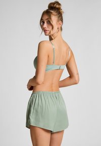Sujetador verde menta y pantalones cortos a juego, fabricados en un tejido suave. El sujetador cuenta con tirantes ajustables y un cierre de gancho; los pantalones cortos tienen una cintura elástica.