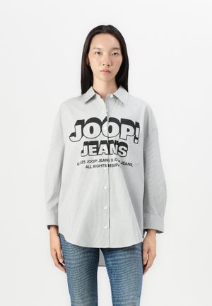 Gestreiftes graues Hemd mit einem großen schwarzen "JOOP! JEANS"-Grafik auf der Vorderseite. Lange Ärmel und lockerer Schnitt. Kombiniert mit Jeans.