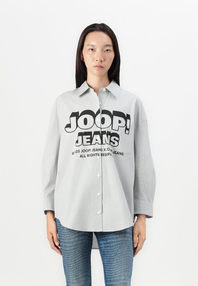 Camicia a righe grigia con un grande grafico nero "JOOP! JEANS" sul fronte. Maniche lunghe e vestibilità relaxed. Abbinata a jeans in denim.