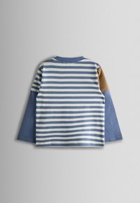 Pruhovaná košeľa s dlhým rukávom v modrej a krémovej farbe, s modrými rukávmi a hnedým akcentom na pleci. Mäkko bavlnené materiály.