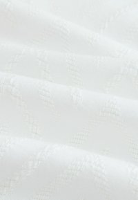 Weißer gewebter Stoff mit einem strukturierten Diamantmuster. Das Material wirkt glatt mit einem subtilen Glanz und enger Webung.