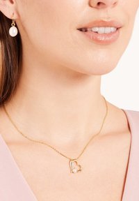 Goudkleurige sieraden met een hart hanger voorzien van een kleine parel en een sprankelend accent, gecombineerd met een bijpassende parel-druppeloorbel.