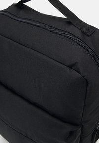 Black padded backpack with a textured fabric, featuring a zippered top, reinforced handles, and multiple front pockets for storage.