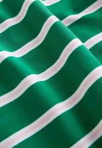 Vihreä kangas, jossa on tasaisesti sijoitetut vaakasuorat valkoiset ja vaaleanpunaiset raidat, pehmeät laskokset ja teksturoitu neulekuvio.