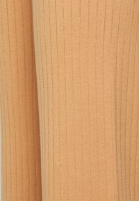 Tecido ribado em um suave tom pêssego, apresentando uma superfície texturizada e linhas verticais, proporcionando um ajuste justo e ligeira elasticidade.