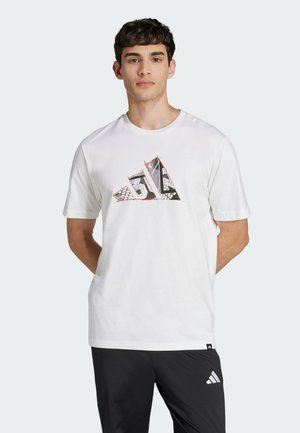 Camiseta de algodón blanca con un diseño gráfico en negro y rojo del logo de Adidas en el frente. Mangas cortas y estilo de cuello redondo.